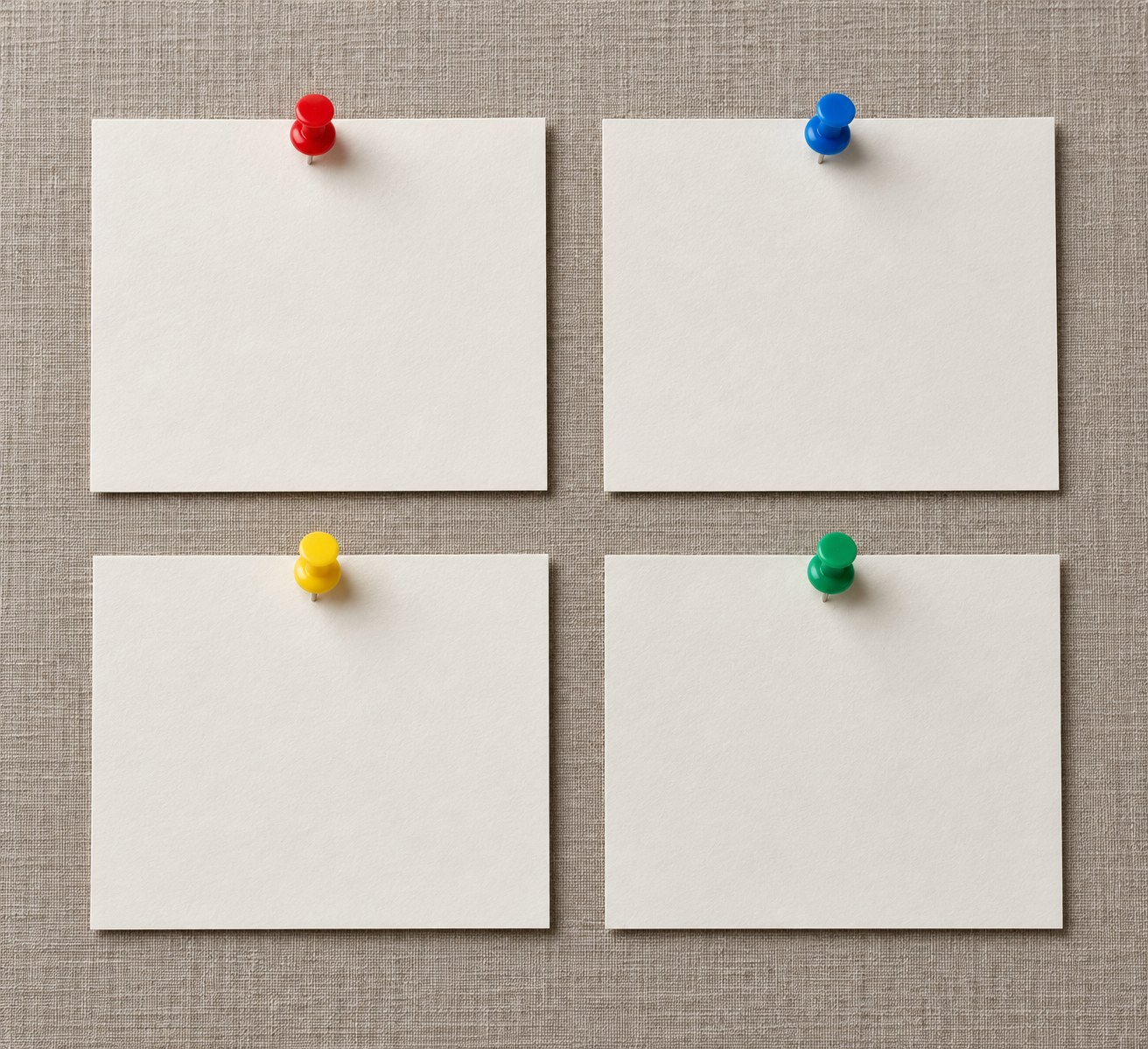 Four blank paper cards in a grid, each fixed with a different colored pushpin