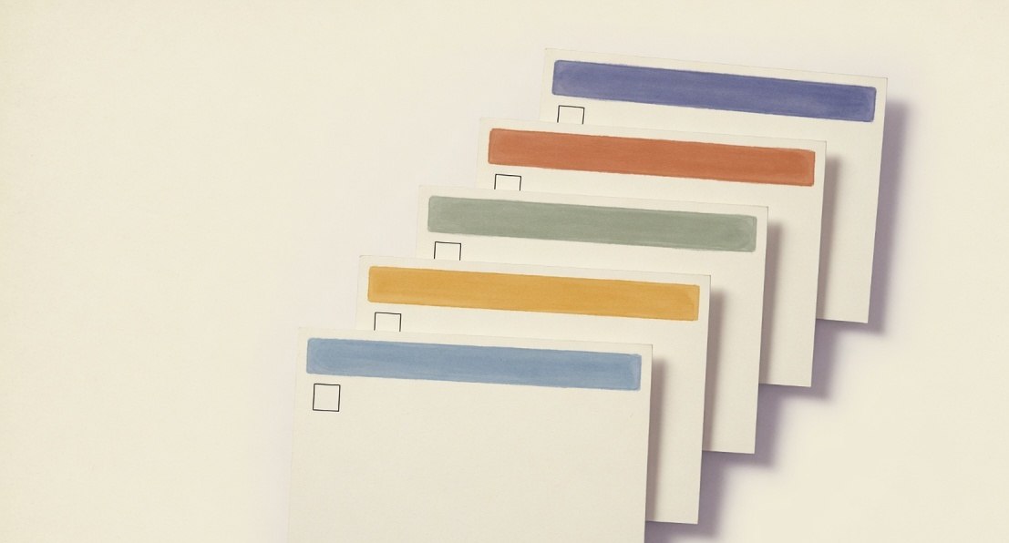 Five blank paper checklist cards with colored header bands and empty checkboxes, fanned on a desk